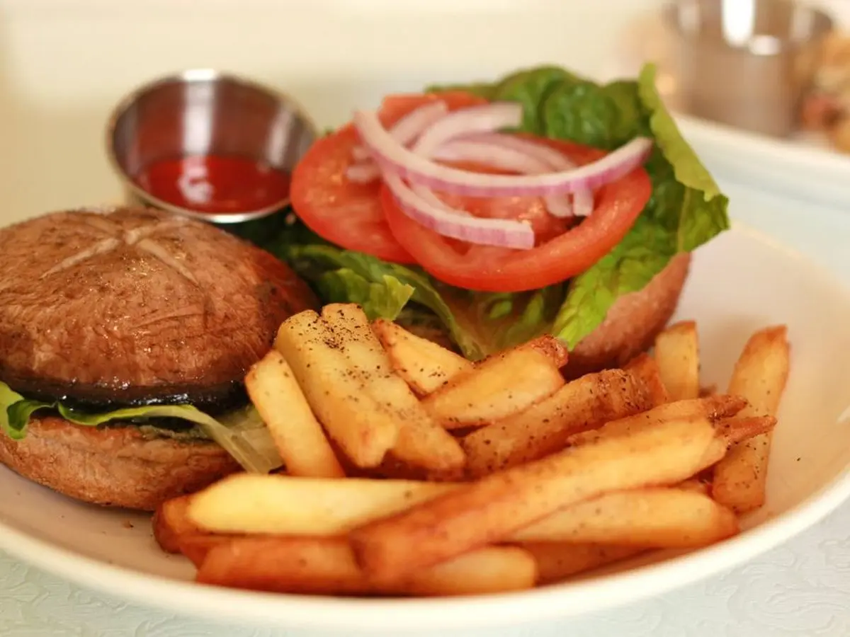 Hamburguesa con pan de champiñón portobello, lechuga, tomate y cebolla morada, con patatas fritas