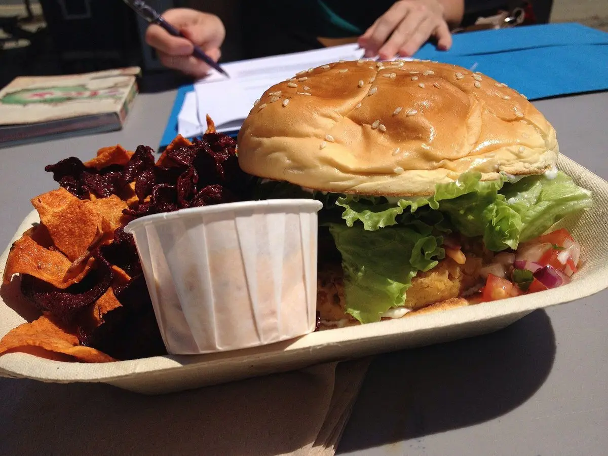 Hamburguesa vegetal de garbanzo en pan con lechuga y tomate, acompañada de chips de boniato y remolacha