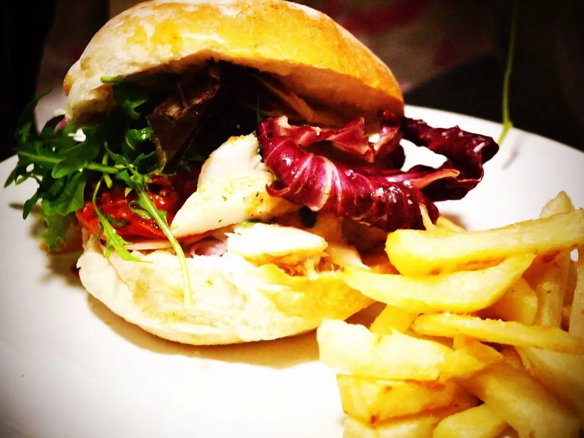 Hamburguesa de pescado en pan con radicchio y patatas fritas