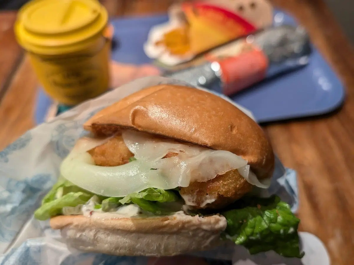 Hamburguesa en pan con lechuga, cebolla y queso fundido sobre papel de envolver