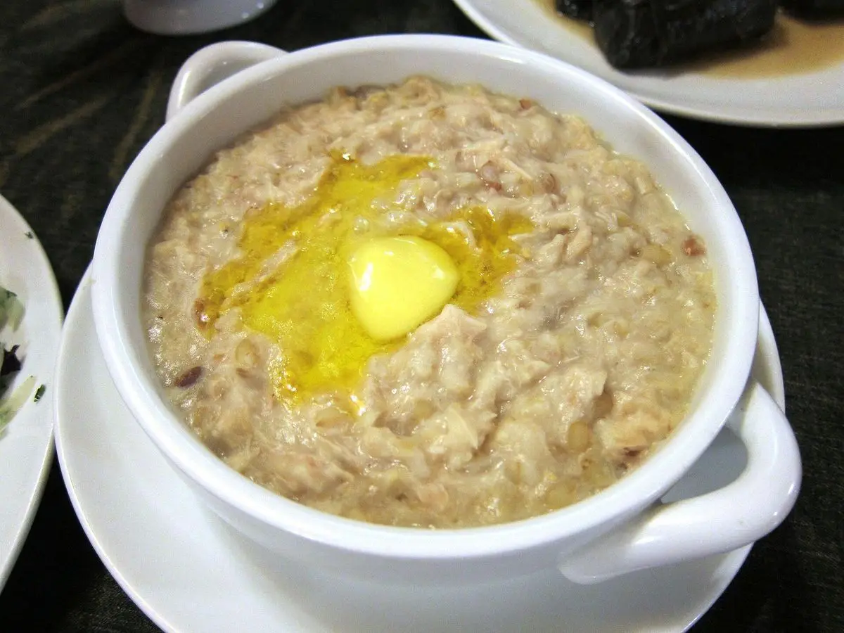 Cuenco blanco de gachas espesas de trigo con pollo desmenuzado y una cucharada de mantequilla derretida