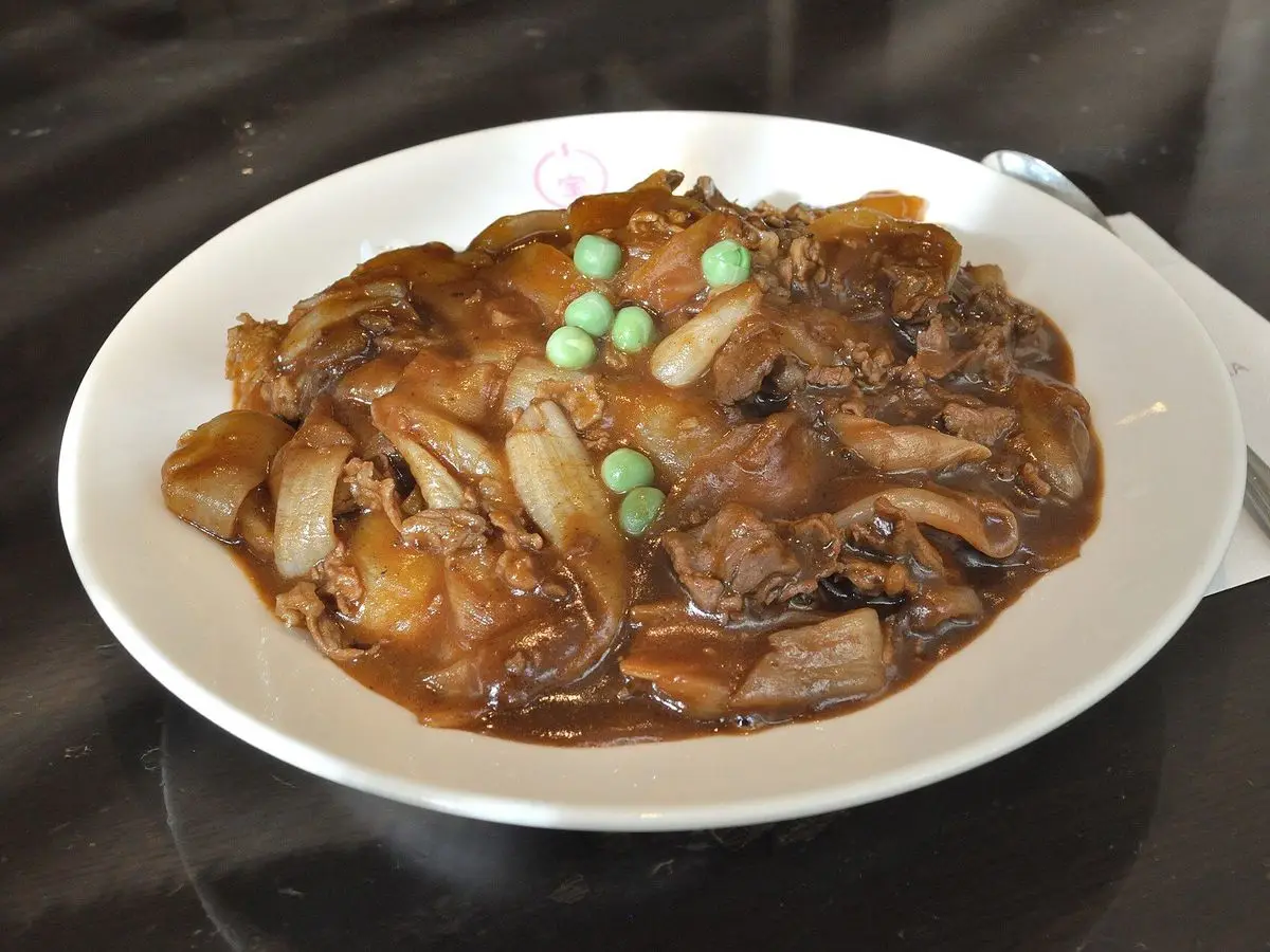Plato de ternera con champiñones y guisantes en salsa oscura sobre arroz blanco