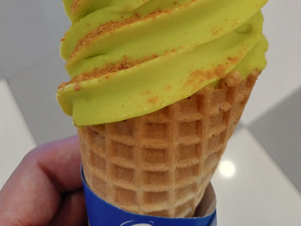 Cucurucho de helado cremoso verde de aguacate en espiral sobre un fondo claro