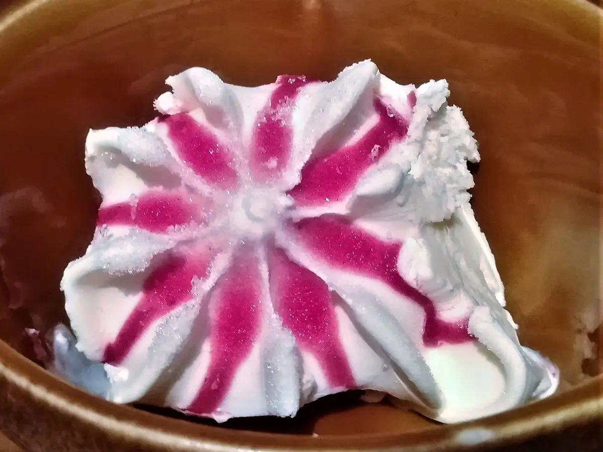 Remolino de helado blanco veteado de frambuesa rosada servido en un cuenco