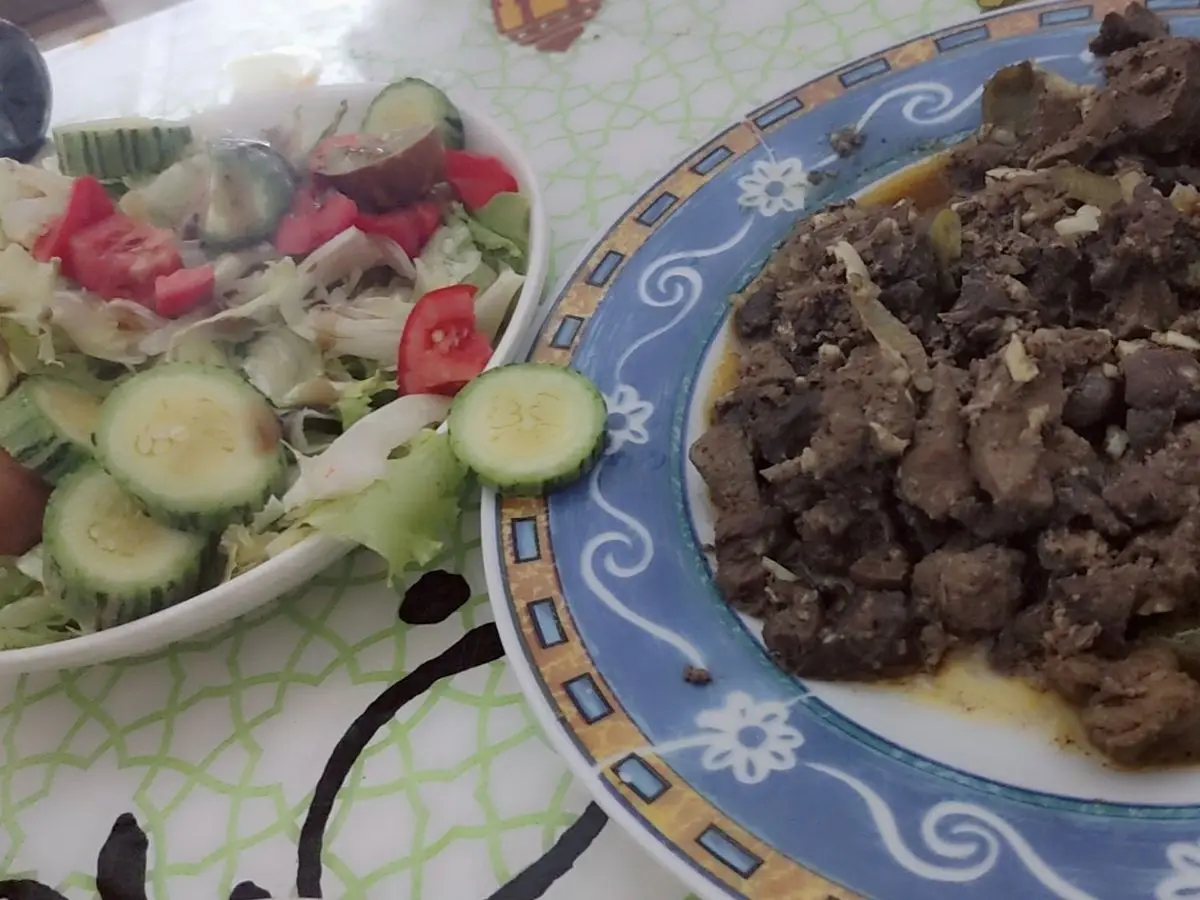 Plato decorado con higaditos de pollo salteados y, al lado, ensalada de lechuga, pepino y tomate