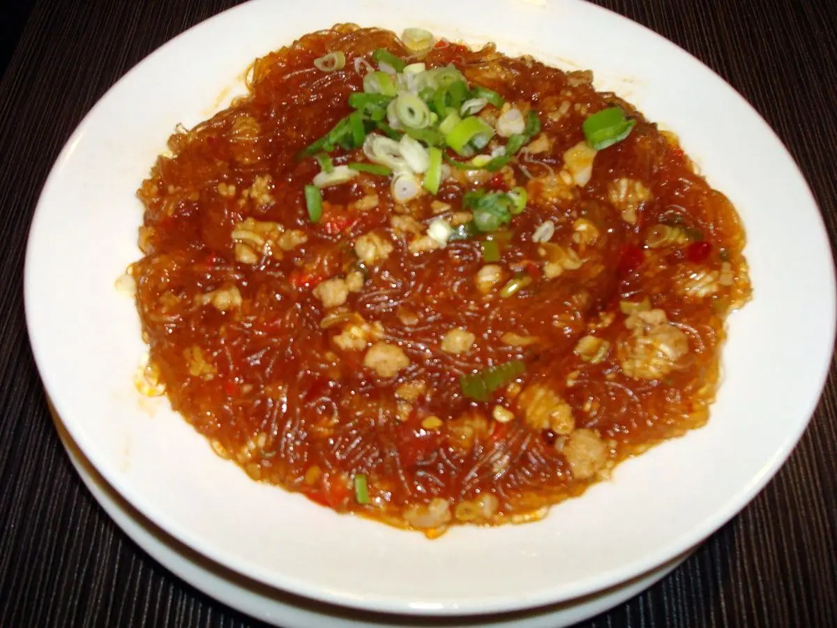 Plato blanco de fideos de cristal con salsa roja picante y cebolleta