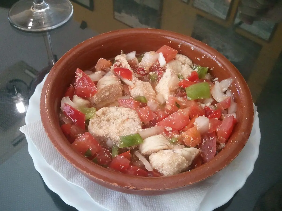 Huevas de merluza aliñadas con tomate, pimiento y cebolla en una cazuela de barro