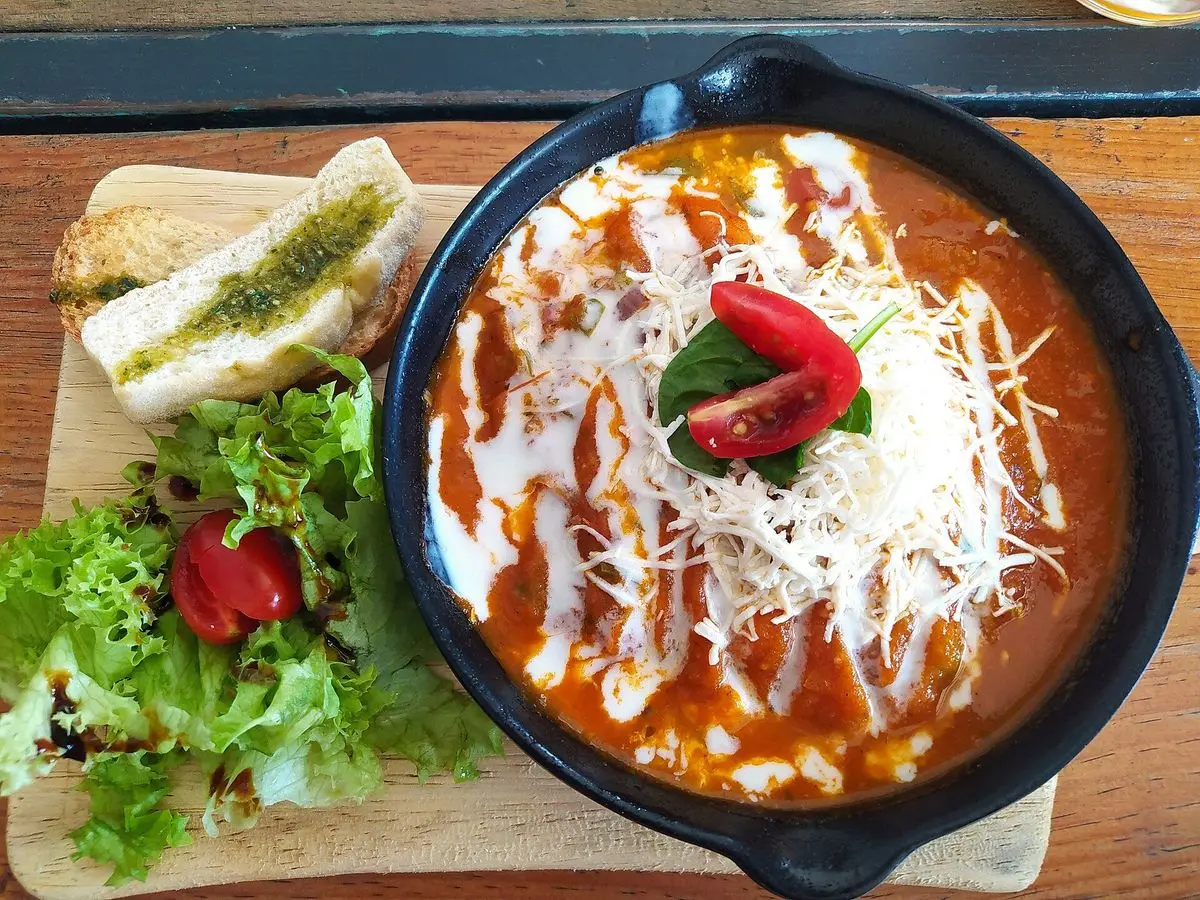 Cazuela de huevos ahogados en salsa roja de tomate con crema y queso rallado por encima