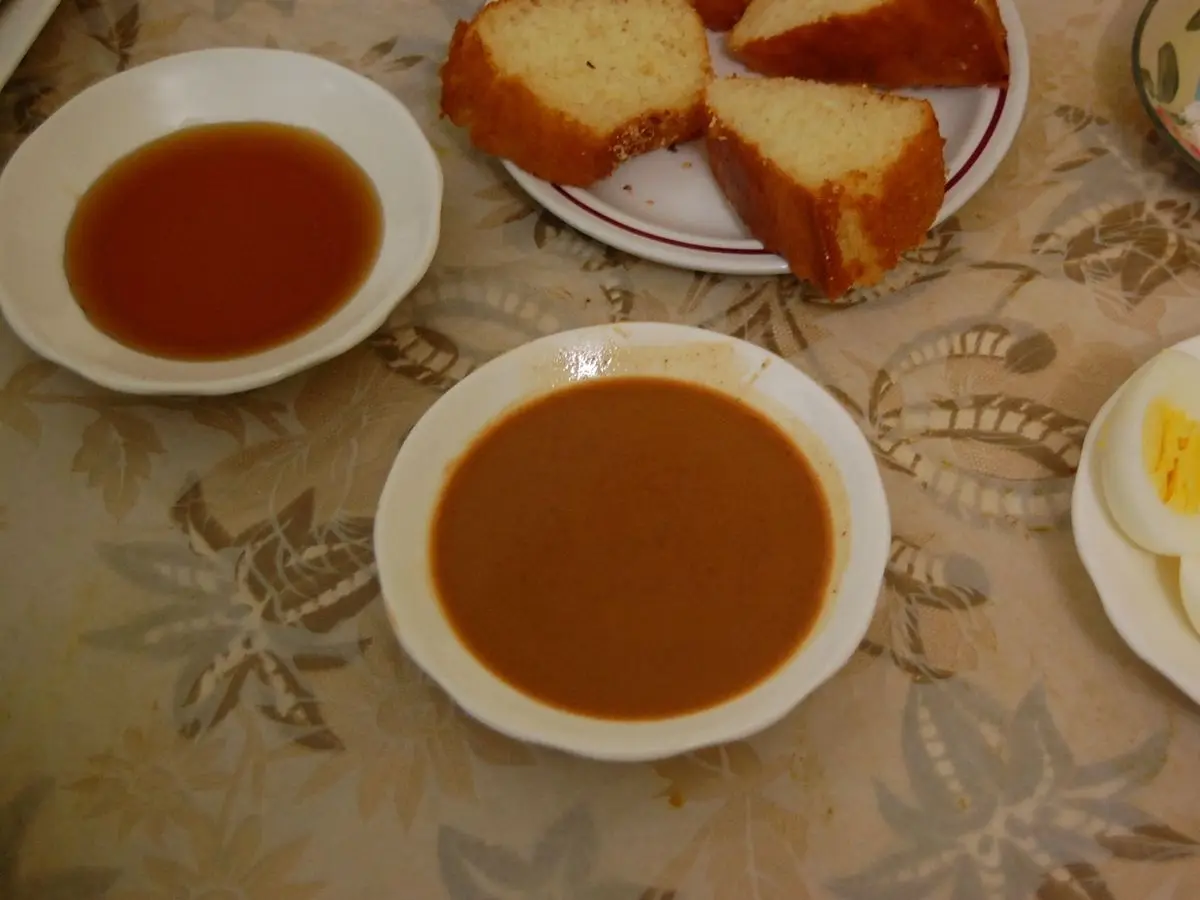 Mesa con cuencos de amlou, pasta de almendra y miel, pan en rebanadas y huevos duros cortados