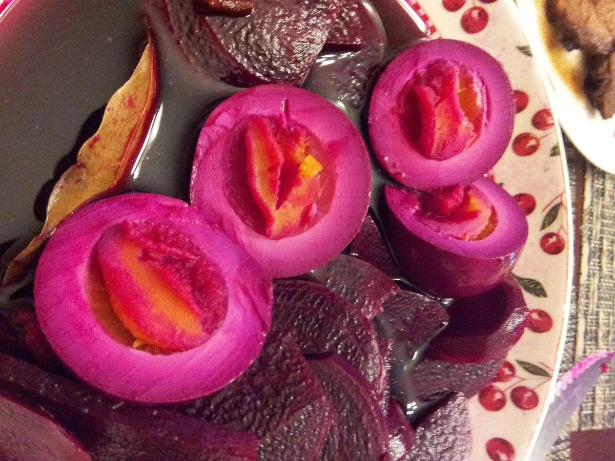 Huevos duros encurtidos teñidos de rosa intenso por la remolacha, partidos por la mitad con la yema naranja
