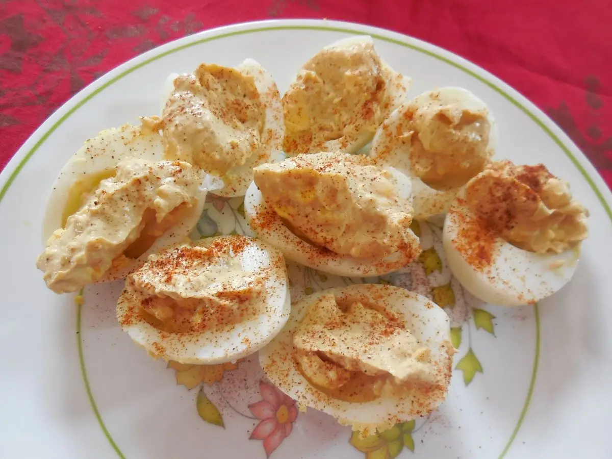 Plato blanco con huevos duros rellenados y dorados por encima, espolvoreados con pimentón