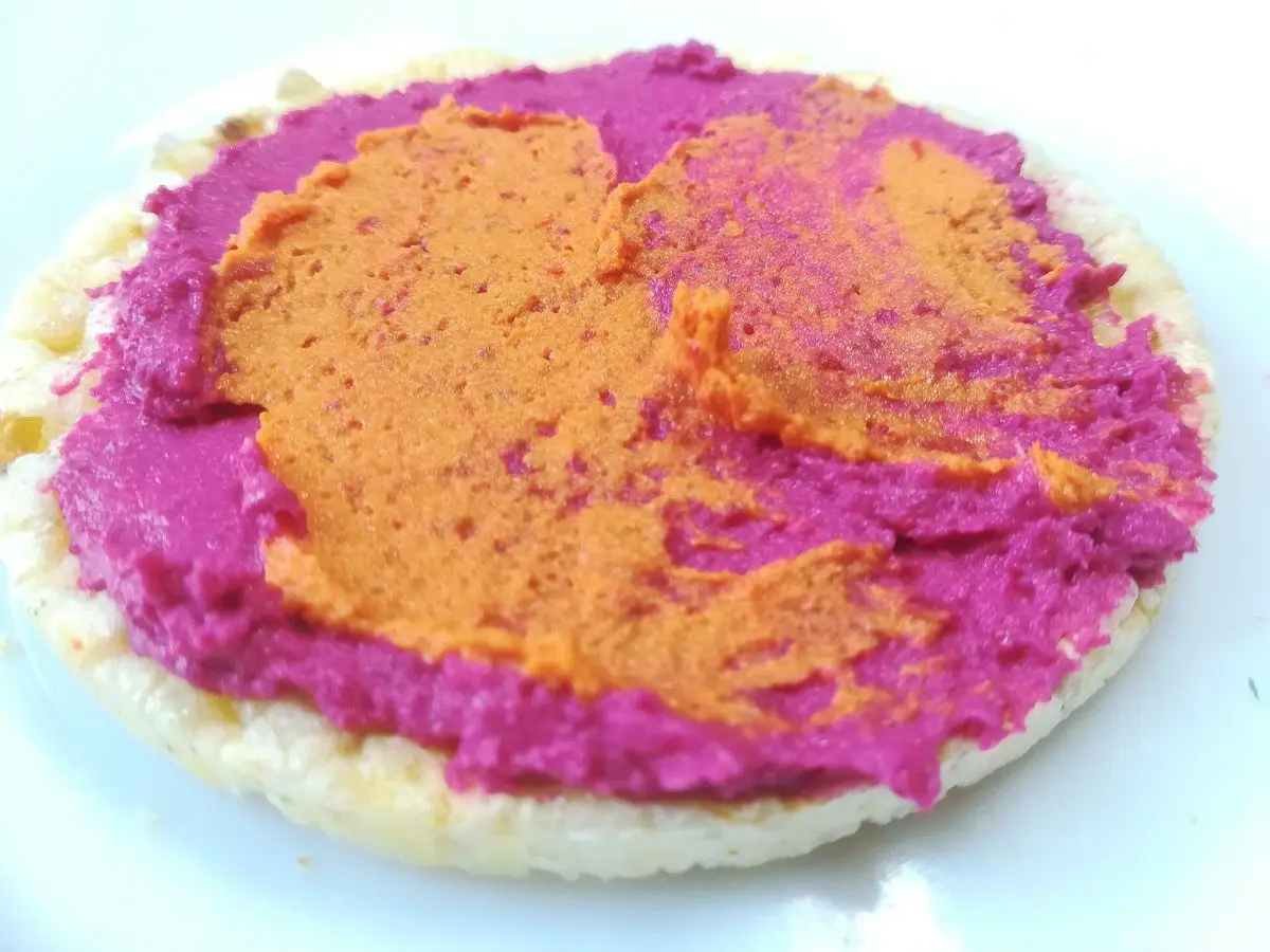 Hummus rosa de remolacha extendido sobre una torta de arroz