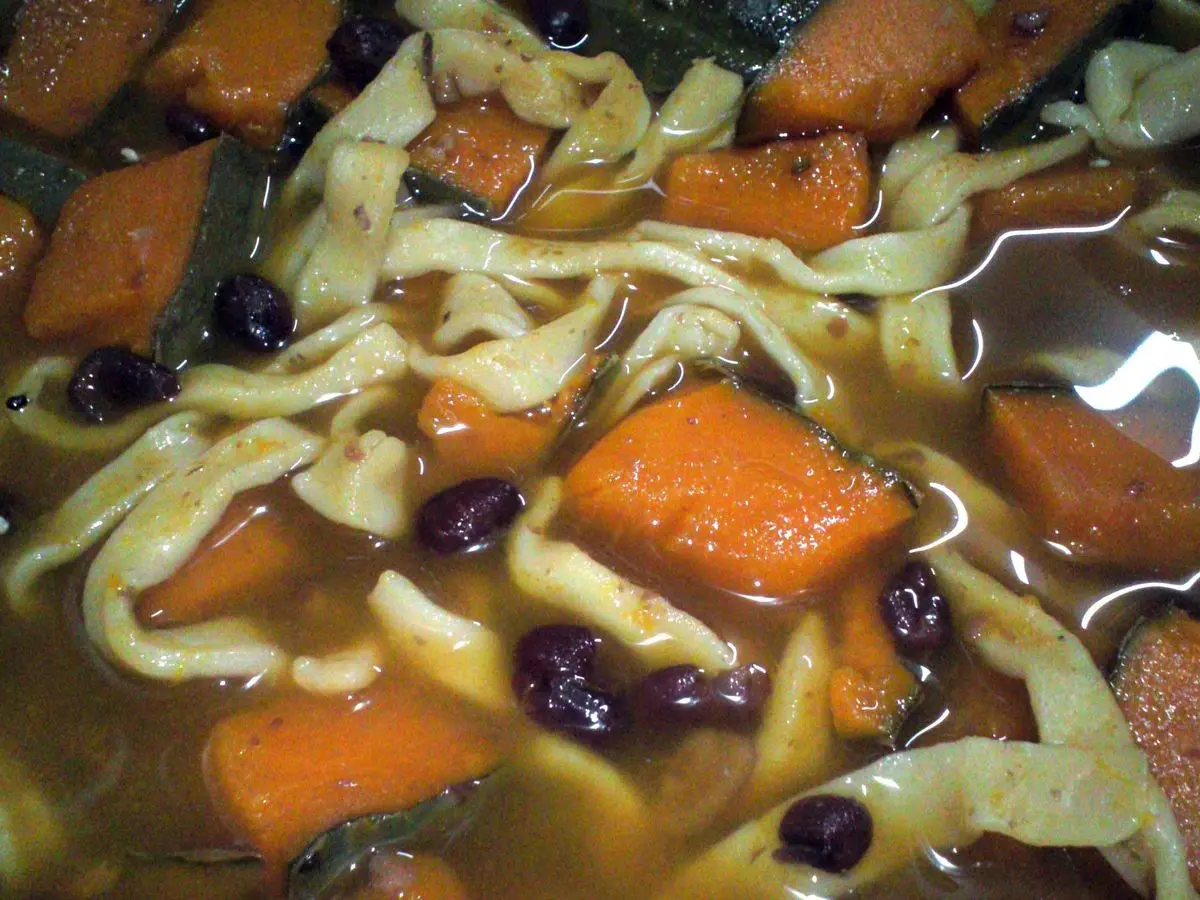 Fideos anchos en caldo con trozos de calabaza naranja y judías azuki