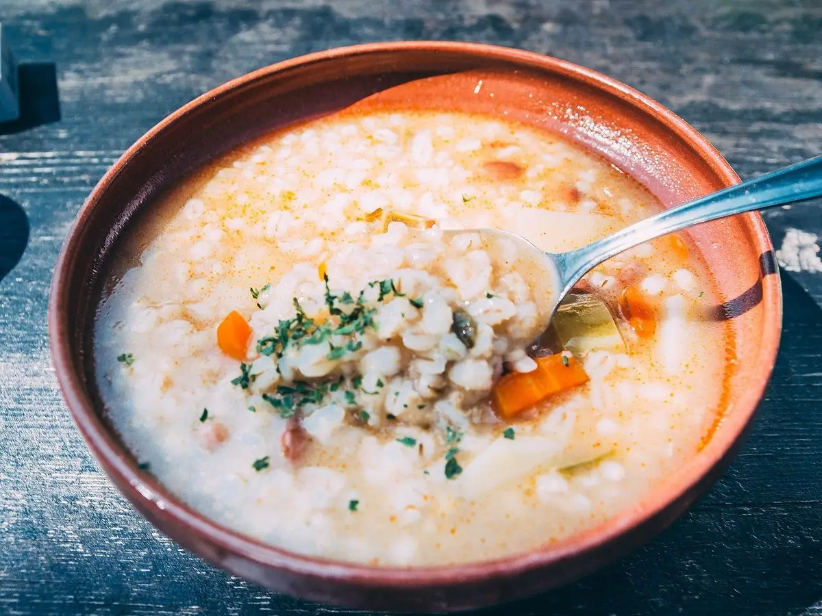 Cuenco de sopa espesa de alubias y verduras con zanahoria y perejil y una cuchara