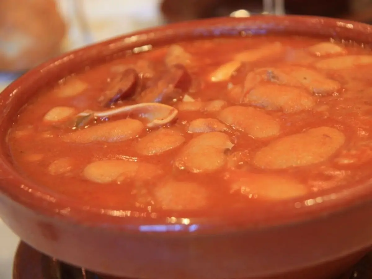 Cazuela de barro con judiones estofados en salsa anaranjada