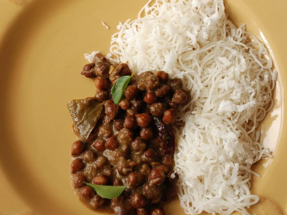 Plato amarillo con curry de garbanzos oscuros y fideos de arroz al vapor