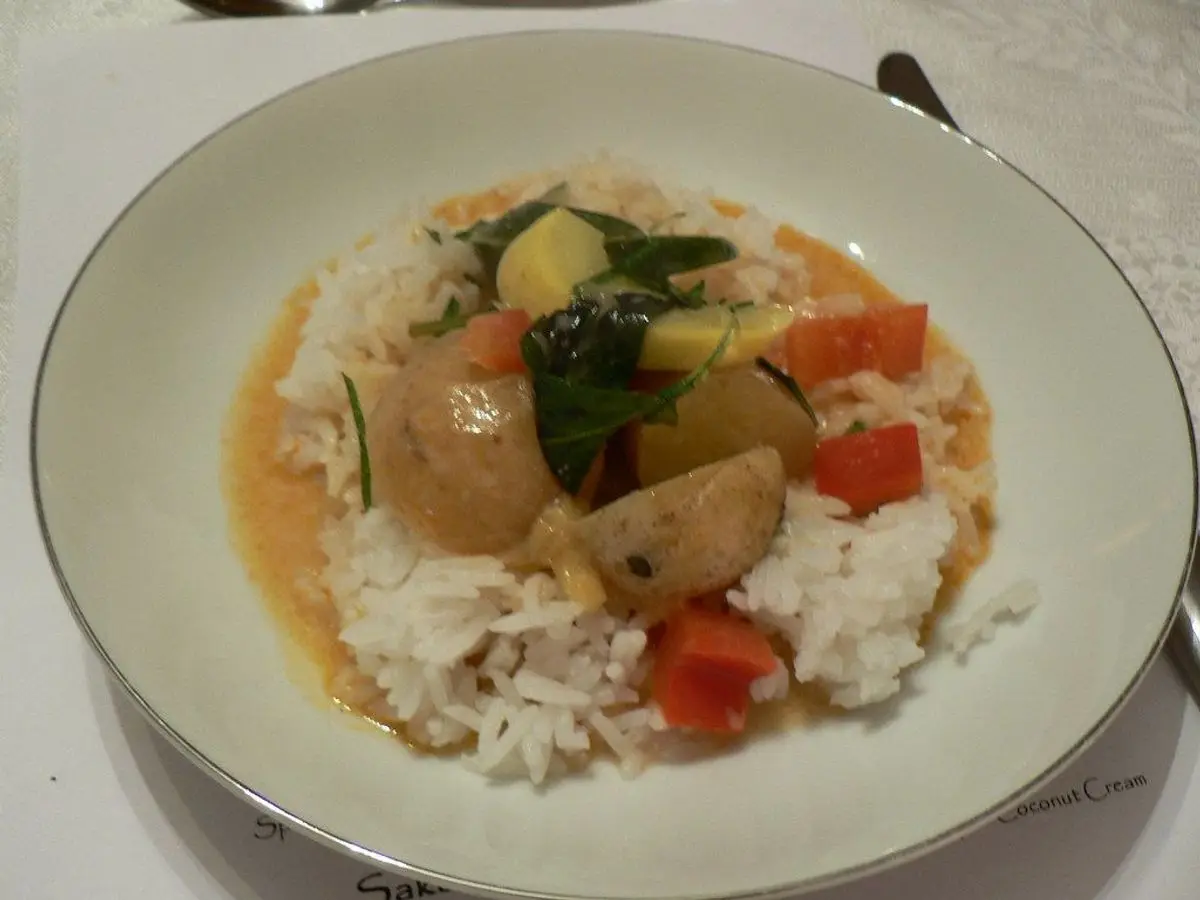 Plato de arroz con curry de verduras, patata y pimiento rojo en salsa anaranjada