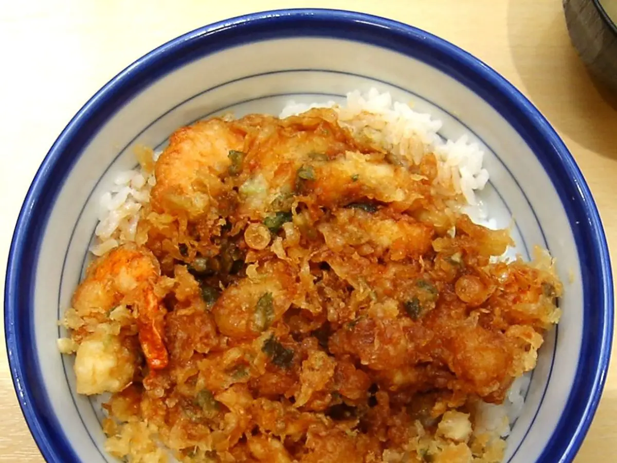 Cuenco de arroz con buñuelo de verduras y gambas fritas con salsa por encima