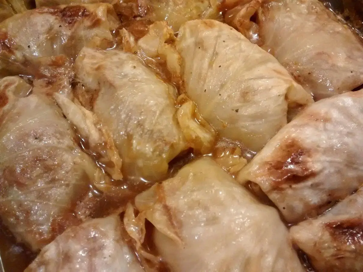 Rollitos de col rellenos de carne al horno dorados en una fuente