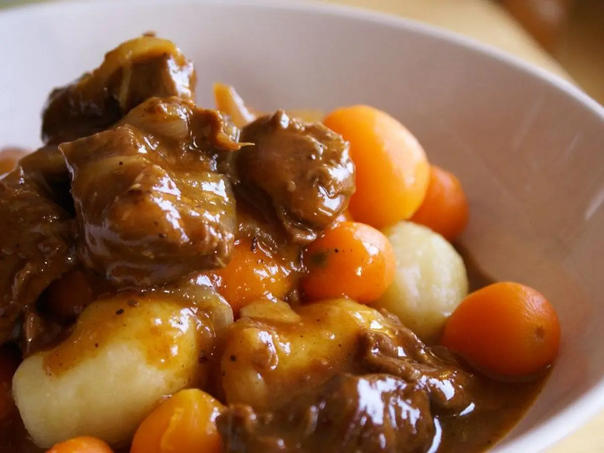 Cuenco de estofado de carne en su salsa oscura con zanahoria y bolitas de patata