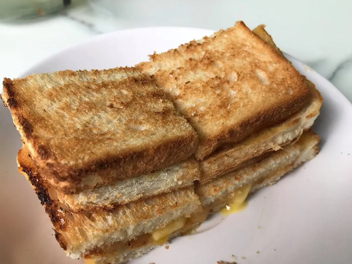 Sándwich de pan tostado con crema de coco cortado en rectángulos sobre un plato blanco