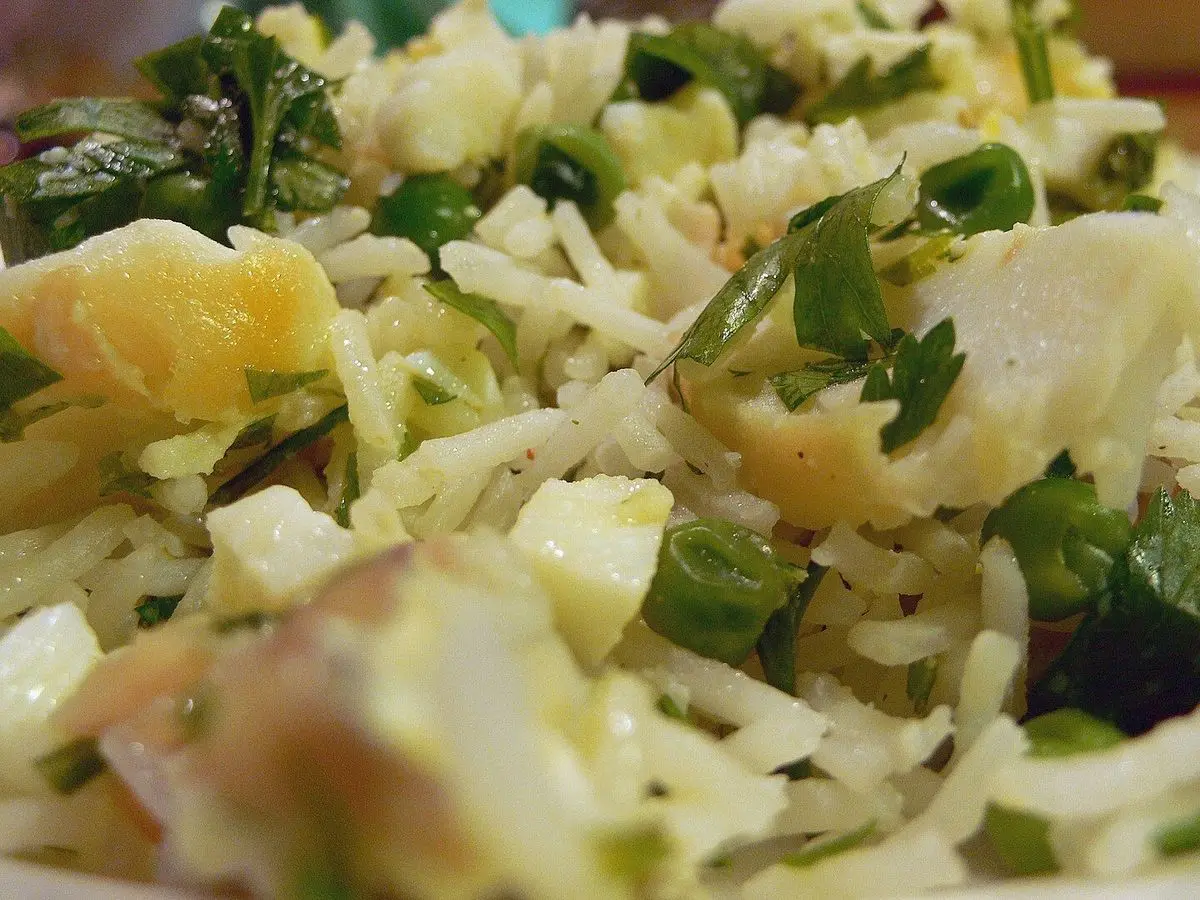 Arroz con trozos de pescado, guisantes y perejil picado servido en un plato