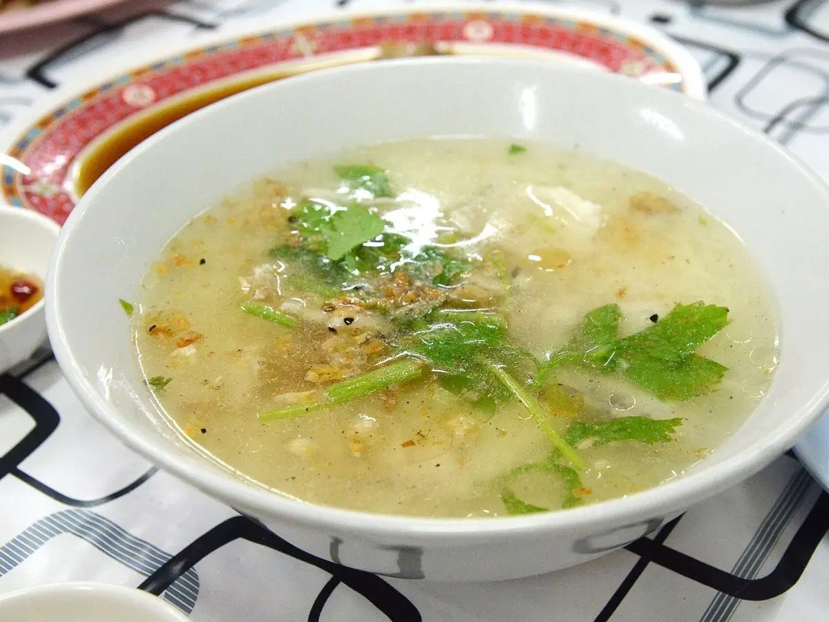 Cuenco de sopa de arroz tailandesa con caldo claro, cilantro y cebolla frita por encima