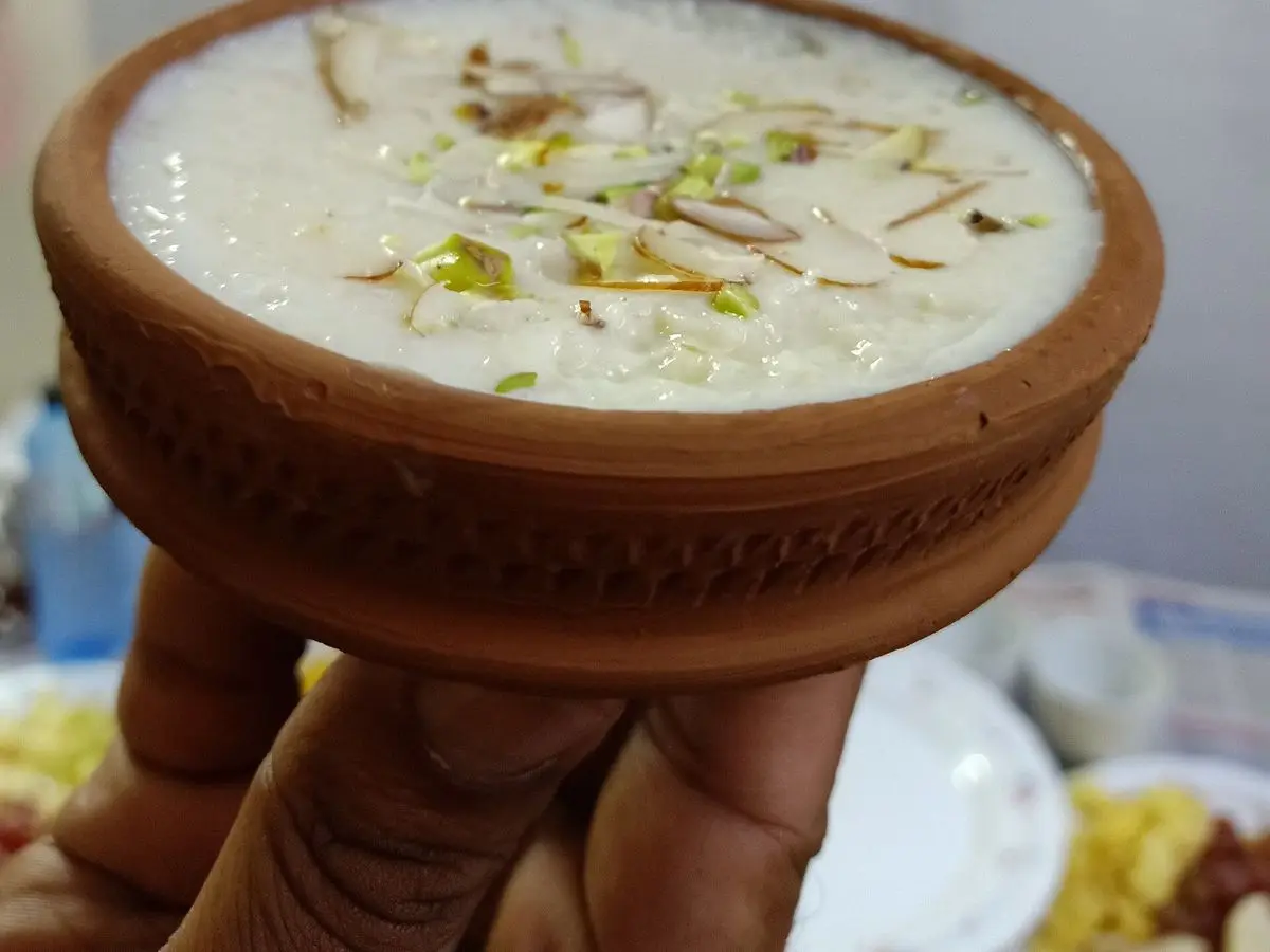 Cuenco de barro con kheer, arroz con leche indio, cubierto de pistachos y almendras laminadas