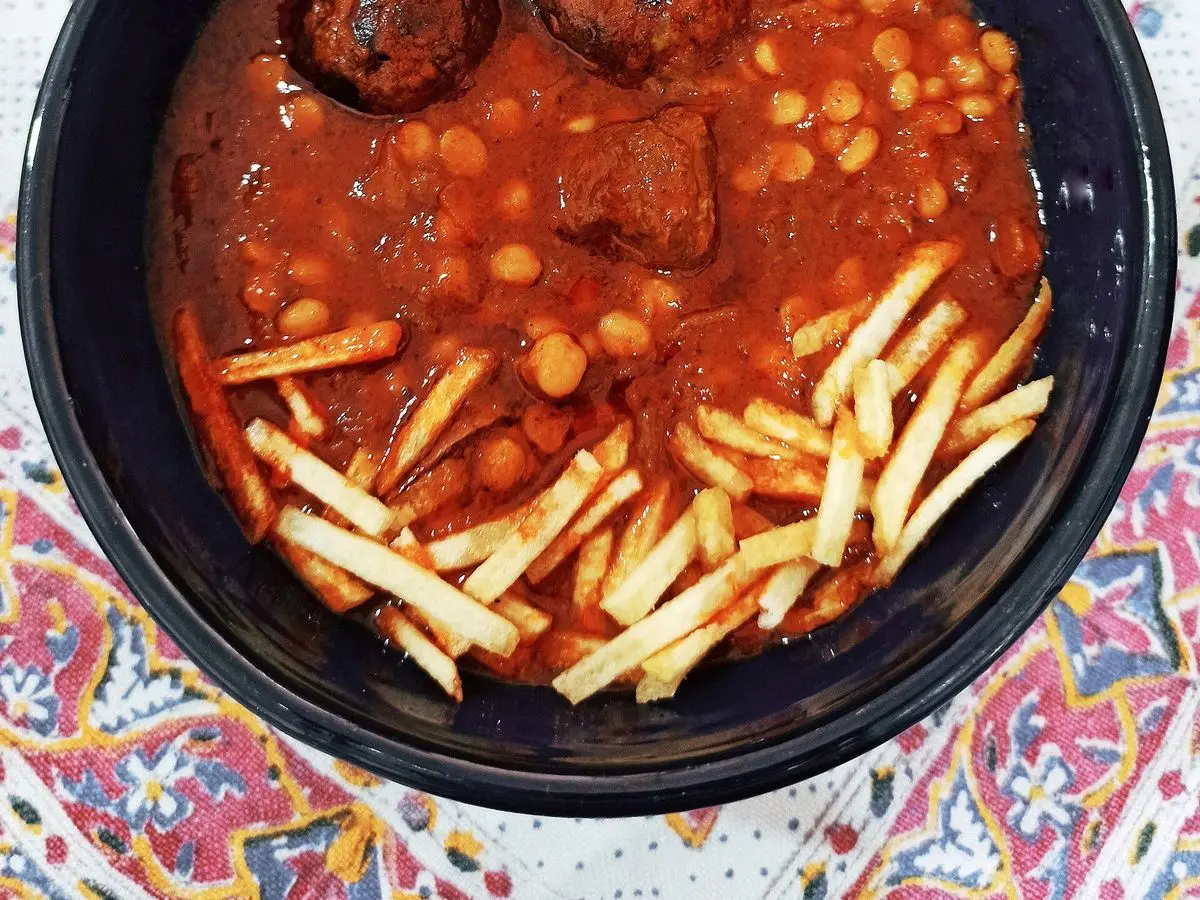 Cuenco de guiso persa de carne en salsa de tomate con guisantes partidos y patatas fritas finas por encima