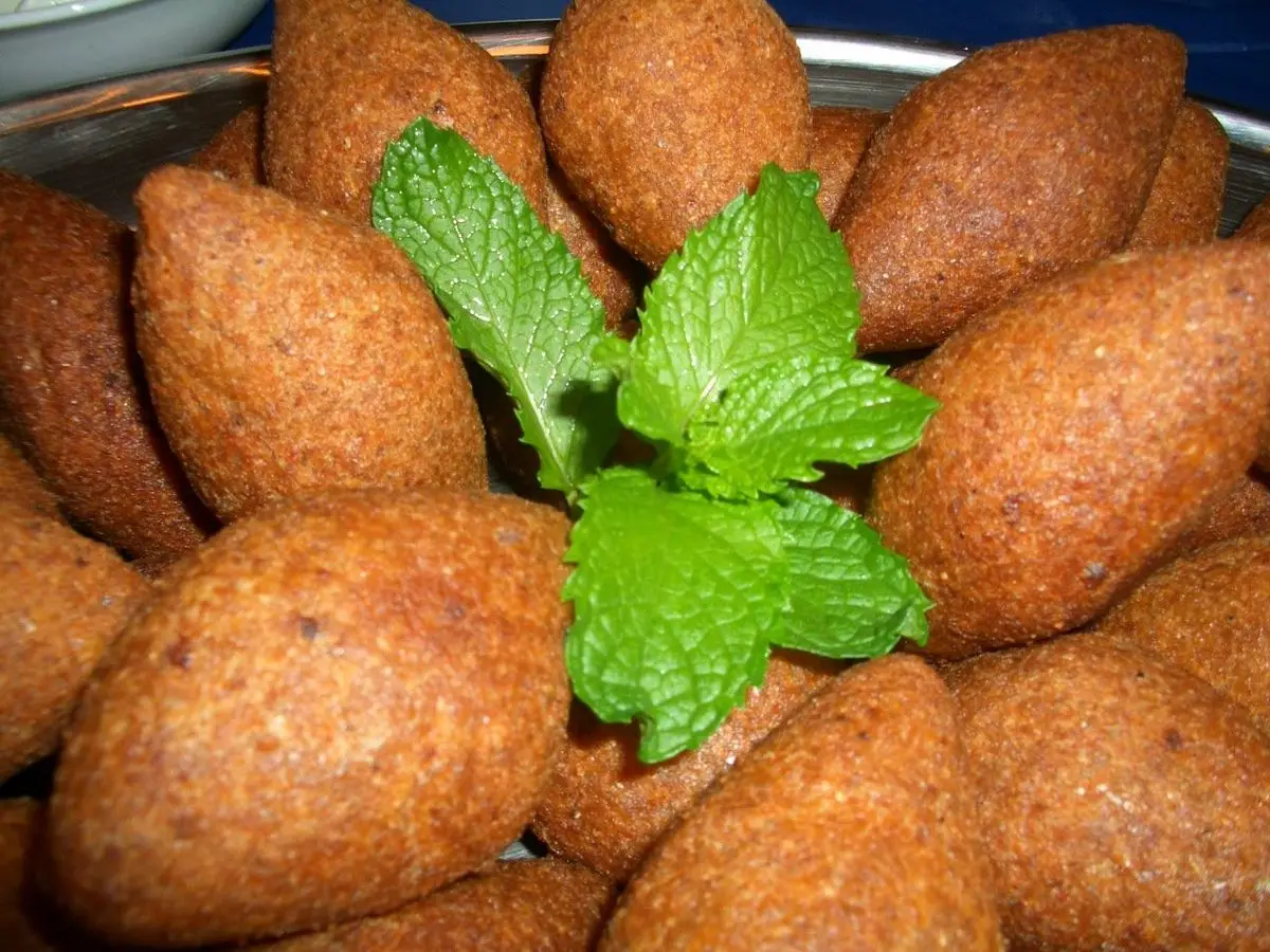 Montón de kibbeh dorados de bulgur con una hoja de menta fresca en el centro
