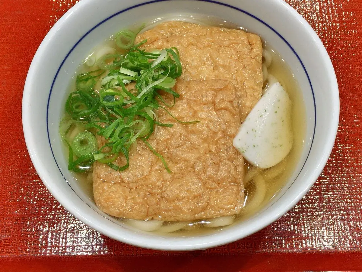 Cuenco de udon en caldo con una lámina de tofu frito dulce y cebolleta picada