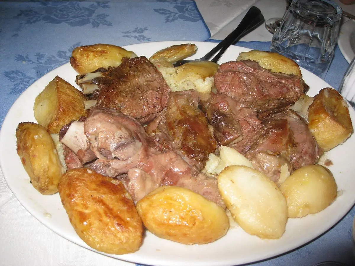 Plato con cordero asado a trozos y patatas doradas al horno