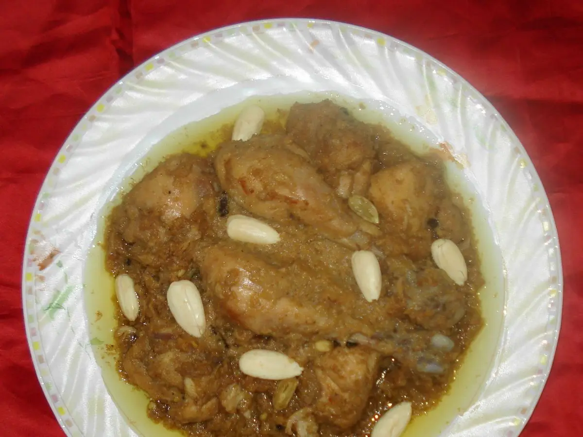 Plato de korma blanco de pollo con almendras laminadas en una salsa cremosa sobre plato blanco