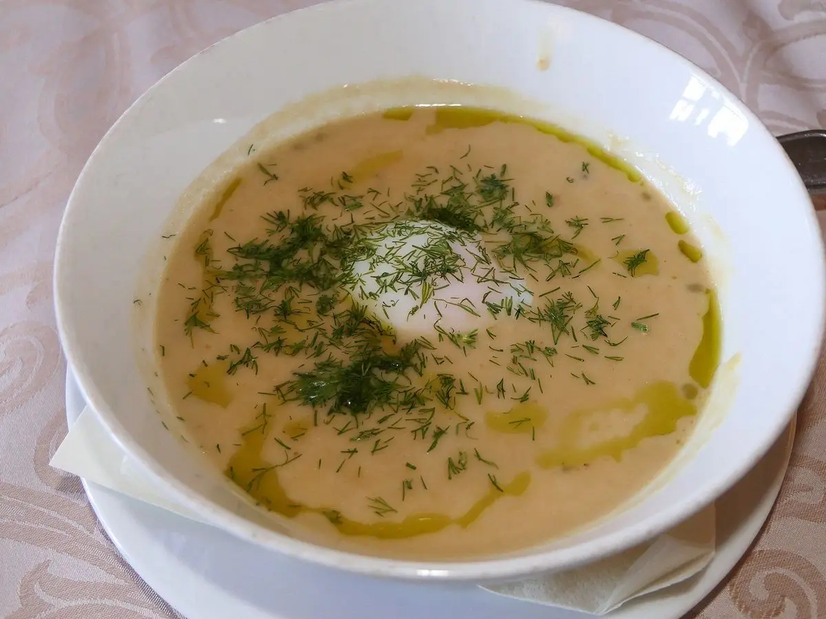 Cuenco de sopa cremosa con eneldo, aceite verde y un huevo escalfado