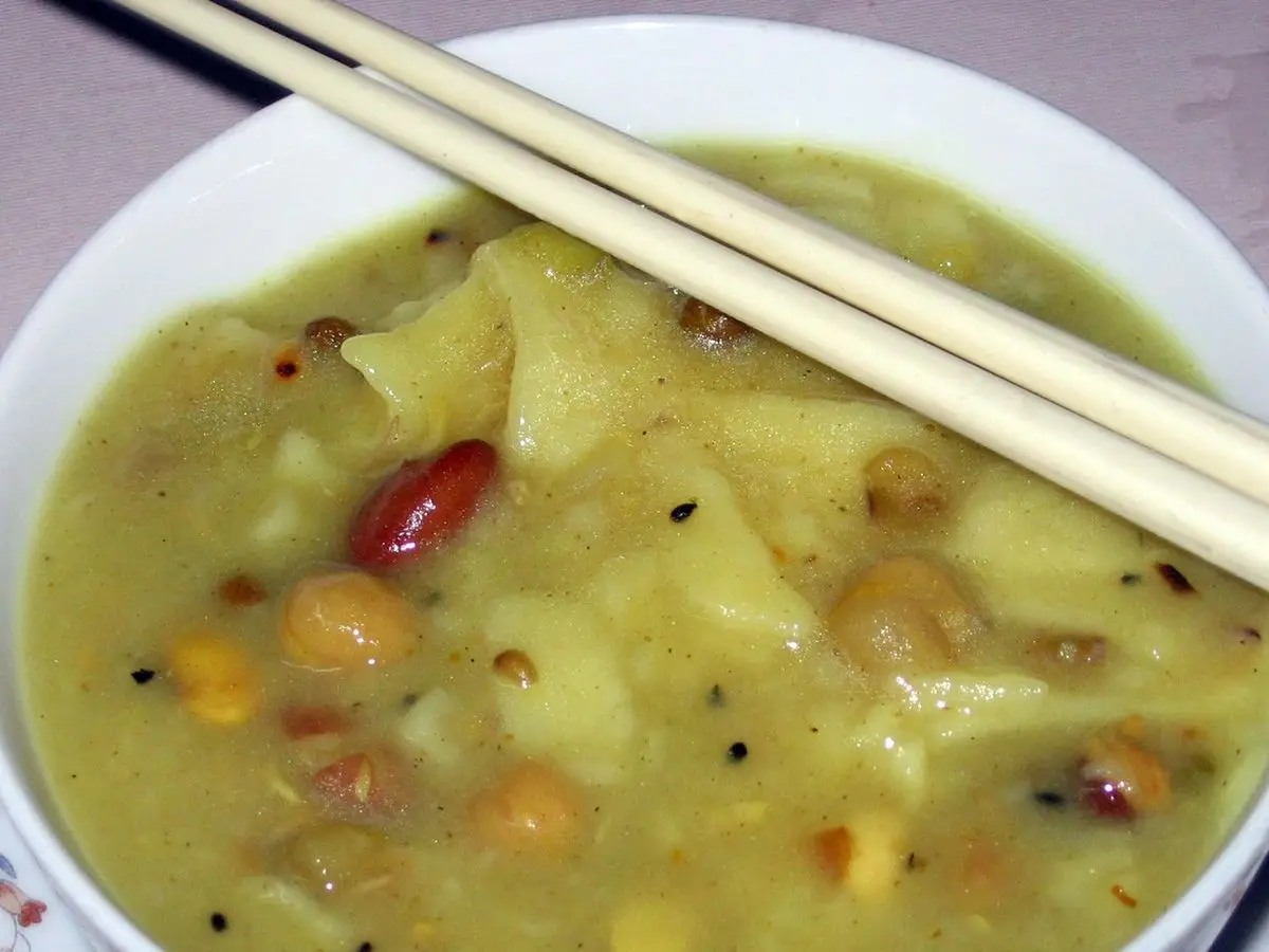 Cuenco de sopa amarilla de legumbres variadas con palillos