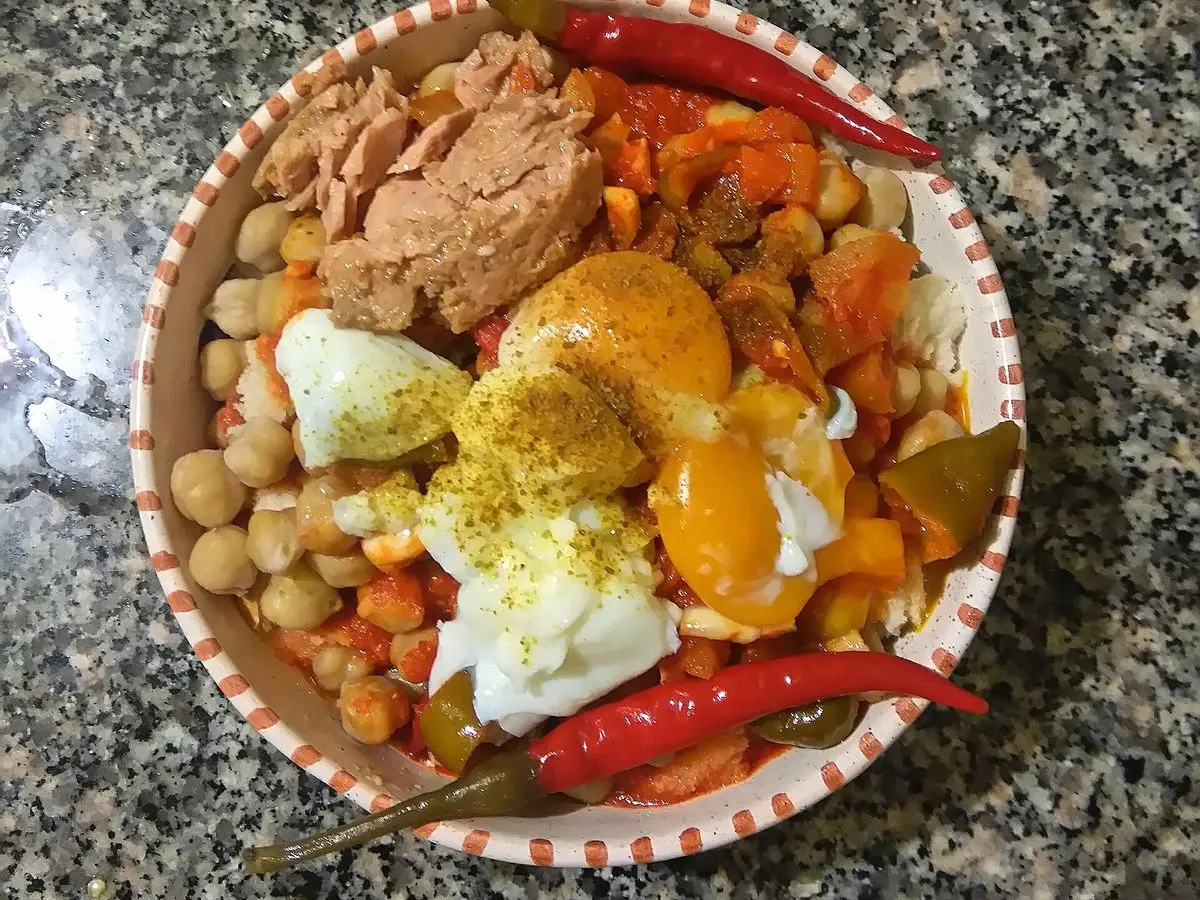 Cuenco con garbanzos, atún desmenuzado, huevo, limón y guindilla roja visto desde arriba