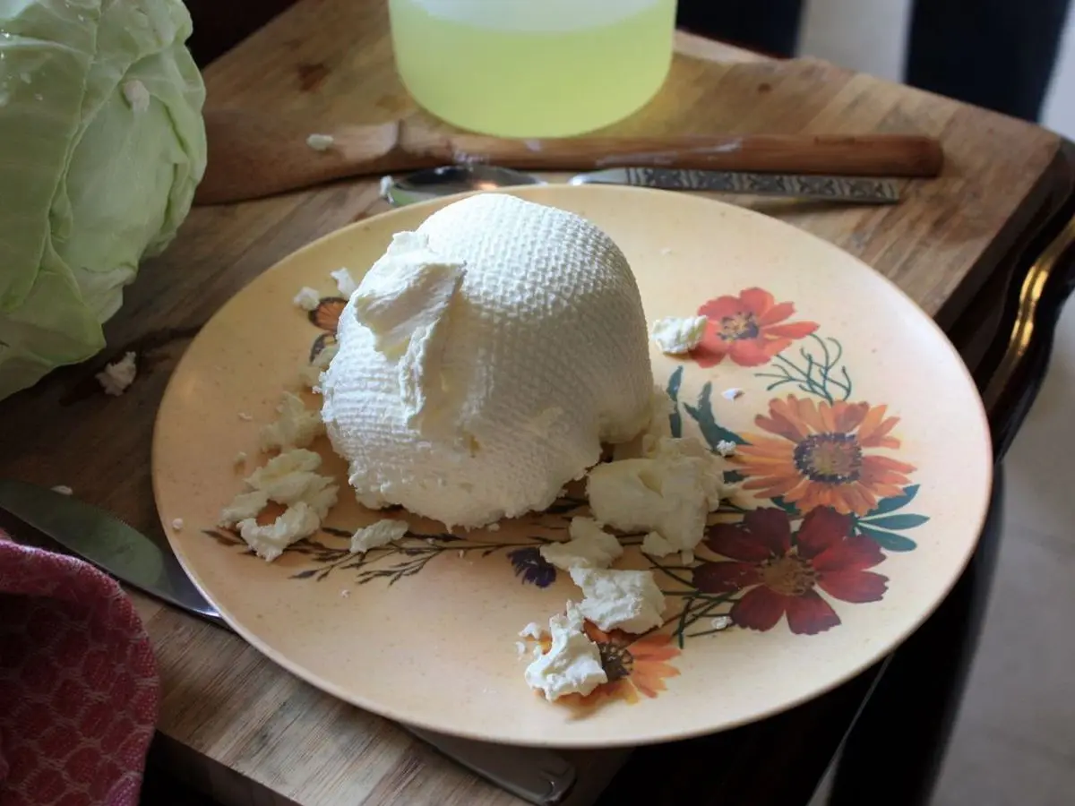 Bola de labneh, yogur escurrido cremoso, sobre un plato de flores en una mesa de madera