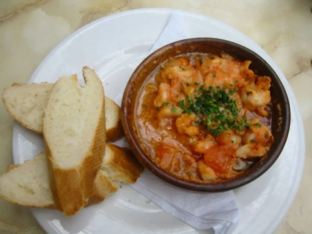 Cazuelita de barro con langostinos en salsa de tomate picante y perejil, con rebanadas de pan