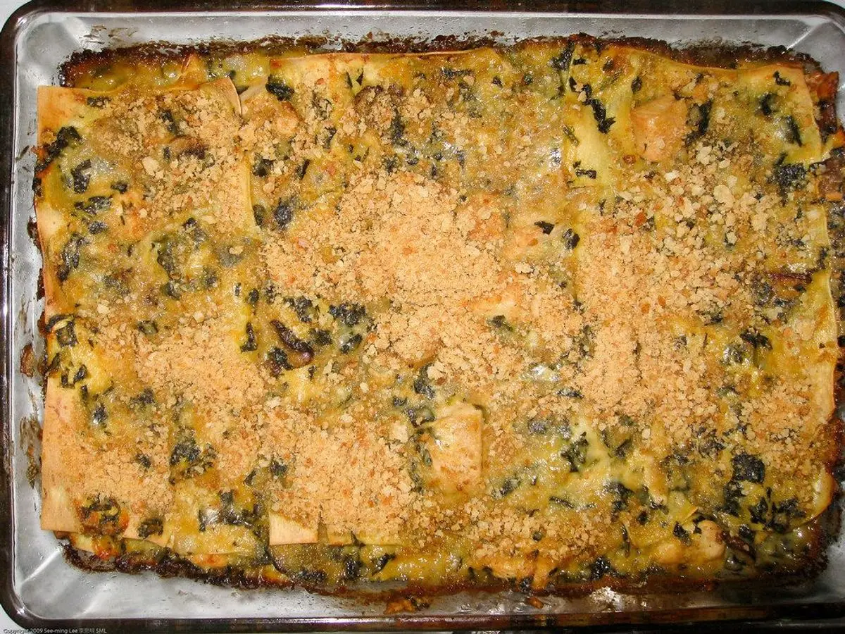 Lasaña gratinada de espinacas con costra dorada en una fuente de cristal