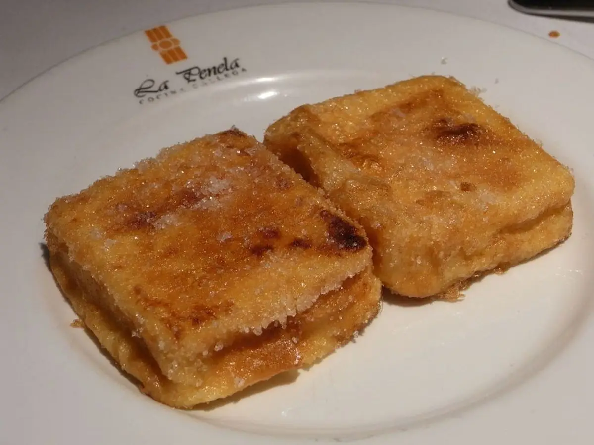 Dos porciones cuadradas de leche frita doradas sobre un plato blanco
