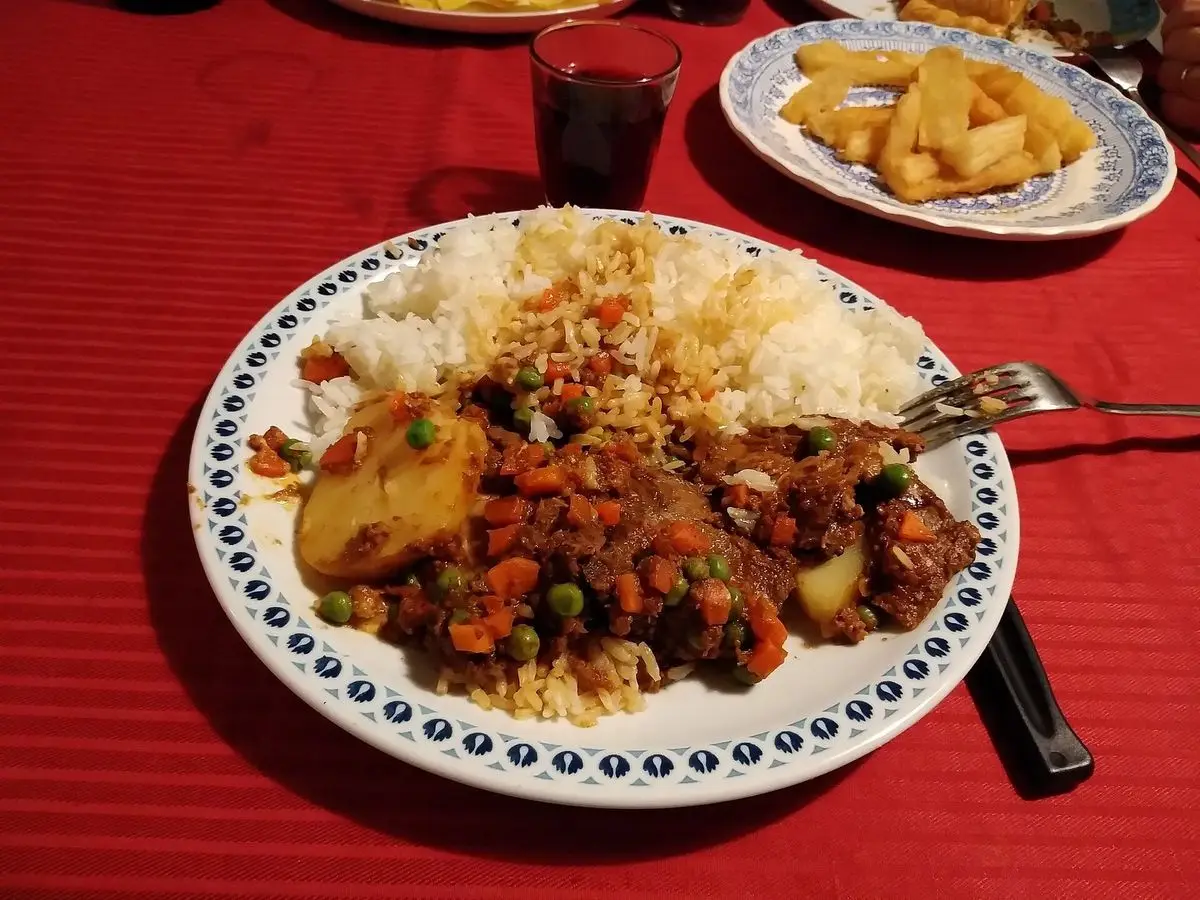 Plato con estofado de lengua con patata y guisantes en salsa roja, acompañado de arroz blanco