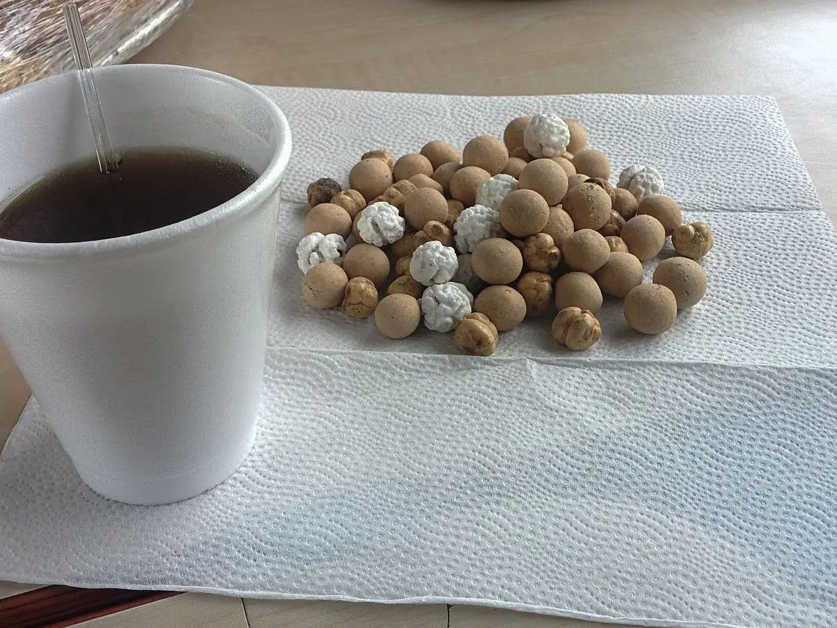Garbanzos tostados con cobertura blanca sobre una servilleta de papel junto a un vaso de té