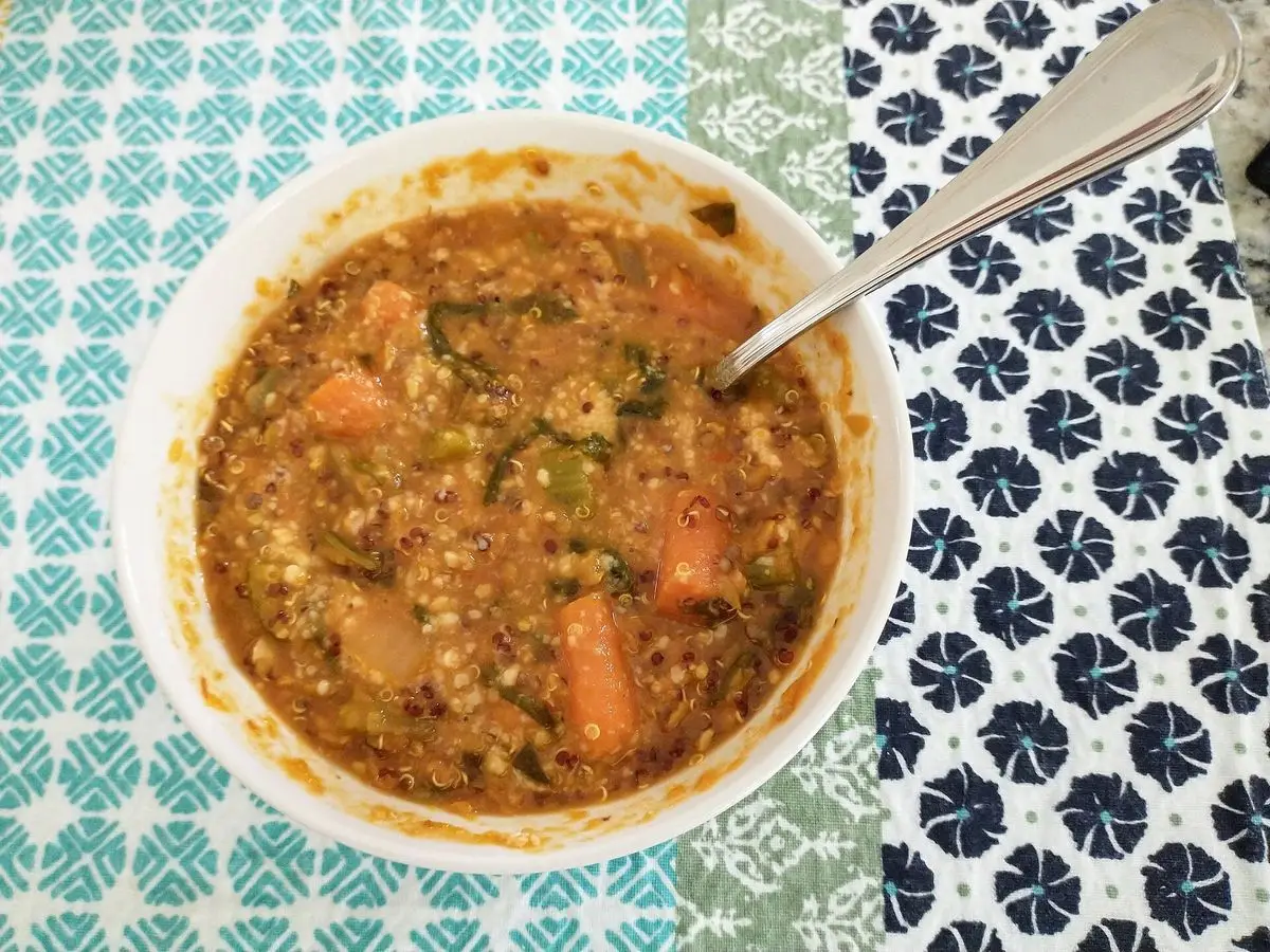 Cuenco de lentejas guisadas con verduras y zanahoria sobre un mantel estampado