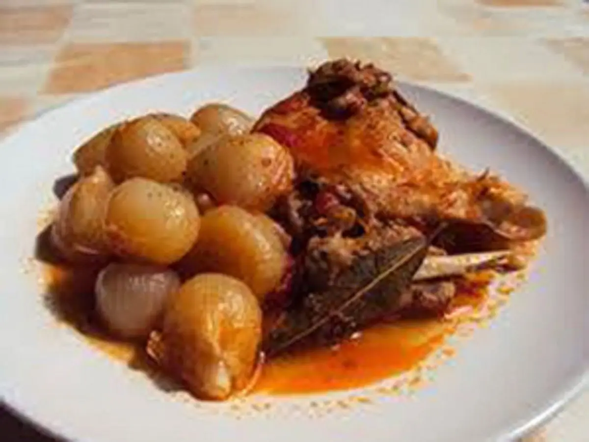 Plato de liebre guisada en salsa oscura con cebollitas glaseadas y hojas de laurel