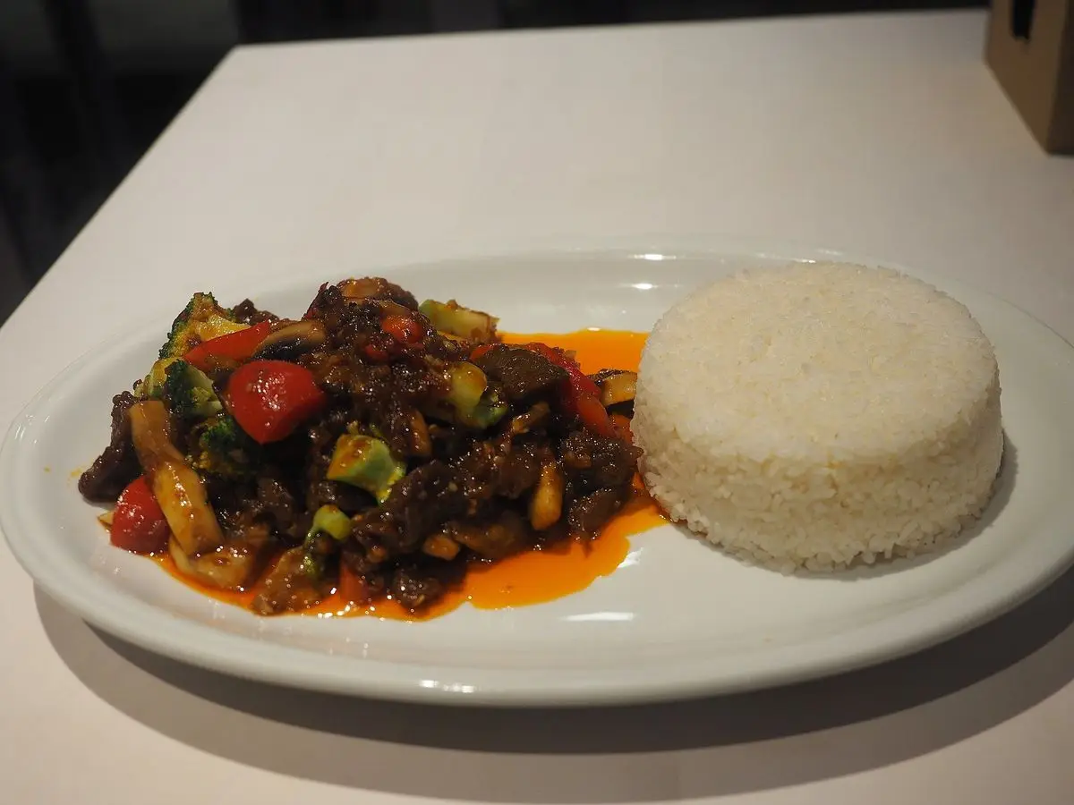 Ternera salteada con verduras y salsa de ostras junto a una porción de arroz blanco
