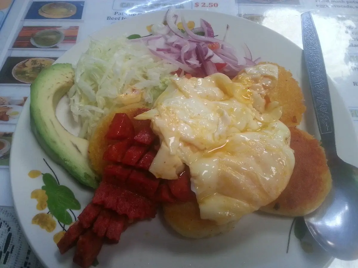 Plato con tortitas de patata, huevo frito, aguacate, lechuga y cebolla morada