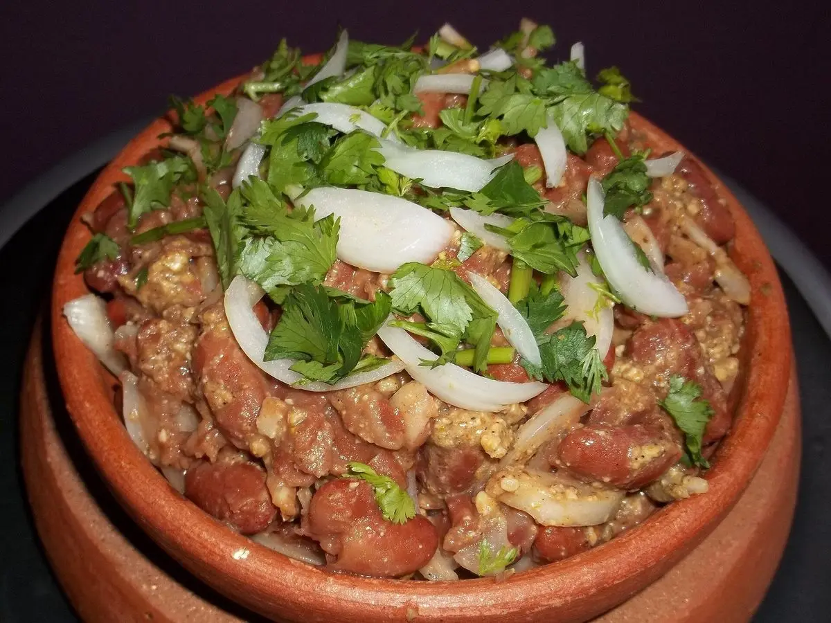 Cazuela de barro con alubias rojas guisadas, cebolla en aros y cilantro fresco por encima