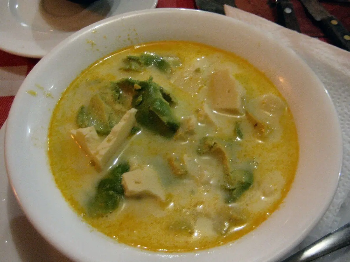 Plato hondo de sopa cremosa de patata con aguacate en trozos y queso