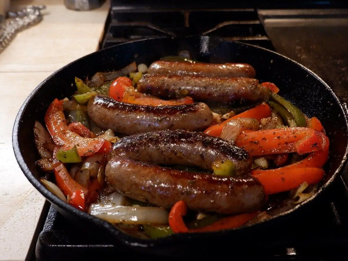 Sartén con salchichas asadas, pimientos rojos y verdes y cebolla