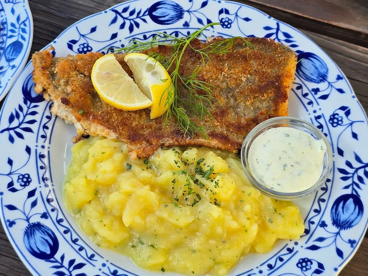 Filete de pescado a la plancha con limón y eneldo, ensalada de patata y salsa en un plato decorado